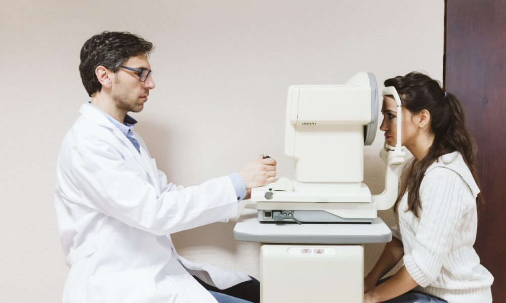 Ophthalmologist man examining young woman eyes in clinic.